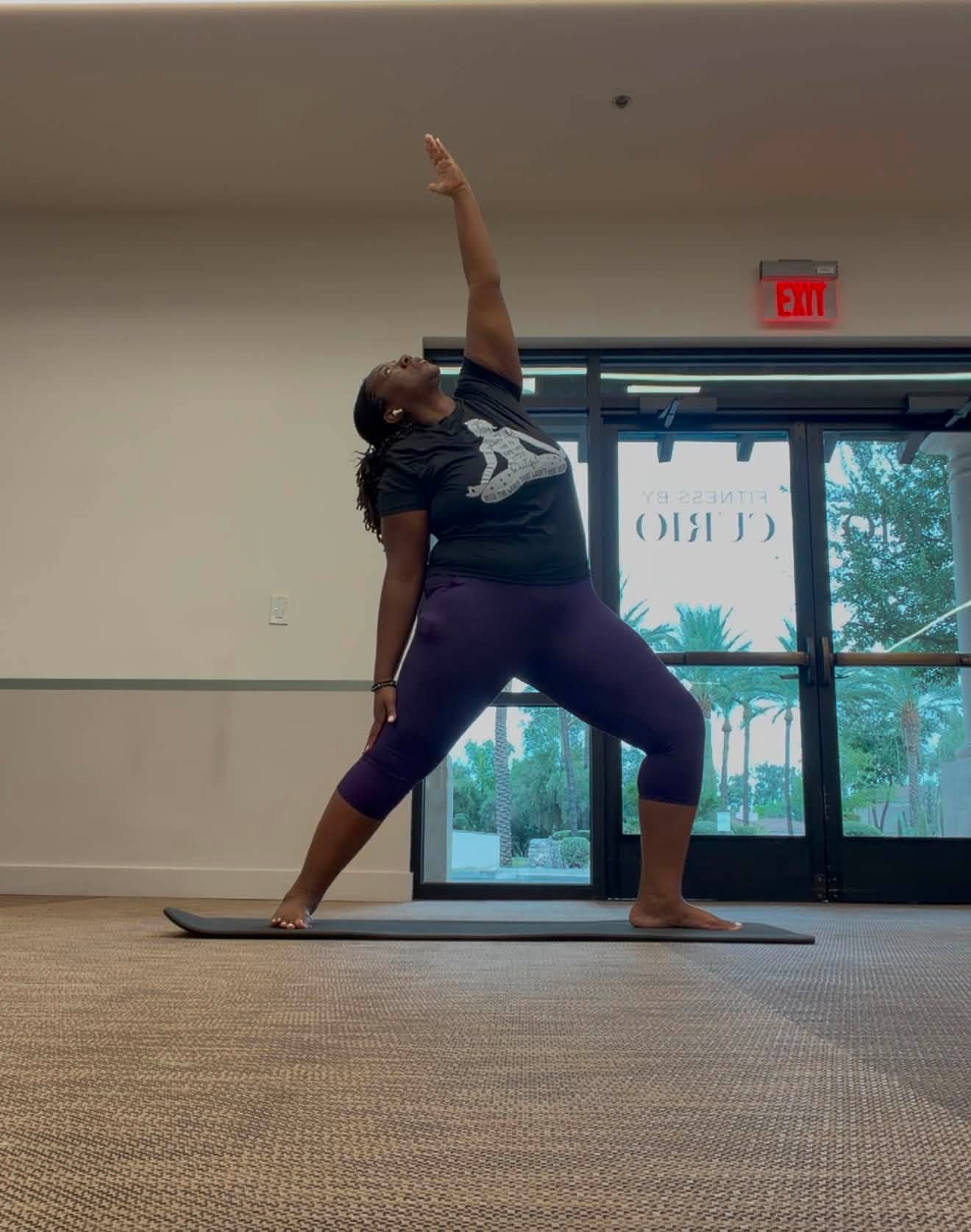 Quisha practicing peaceful warrior pose in a yoga studio